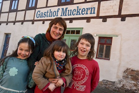 Vor allem junge Familien freuten sich, in Dreiskau-Muckern eine neue Heimat zu finden. Sie lockte die idyllische Lage zwischen Feldern und der neu entstandenen Seenlandschaft; die günstige Verkehrsanbindung nach Leipzig tat ihr übriges dazu. Wenn sie ein Haus kaufen wollten, hatten sie zuvor ein Nutzungskonzept vorlegen müssen, Fördergelder flossen, der Ort mit seinen uralten Dreiseithöfen steht unter Denkmalschutz. Bereits 1995 waren fast alle Häuser verkauft, es entstand wieder ein buntes Dorfleben. Nach Jahrzehnten öffnete der Gasthof, den Ulrike Schröer mit ihrem Mann liebevoll saniert hat, hier mit ihren Kindern Lenea, Alice und Floris. Er ist ein beliebter Treff der Dorfbewohner und Radfahrer aus dem Umland geworden. In dem Gemeindehaus wohnt gleichfalls die Familie Götze. Und in der Kirche, wo in gewachsenen Dörfern der Mittelpunkt des Gemeinsinns ist, hat sich auch in Dreiskau-Muckern eine aktive Kirchgemeinde gebildet, sei es bei einer Tauffeier oder beim Holen des Taufwassers aus dem nahegelegenen Störmthaler See. Das Leben blüht wieder in dem einst dem Tode gewidmetem Dorf.