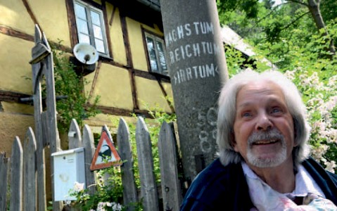 Satellitenschüssel mit Klobürste: Der Schalk Gottfried Reinhardt sitzt schmunzelnd vor seiner Kapitalismuskritik an seinem verlassenem Haus in Obergruna.